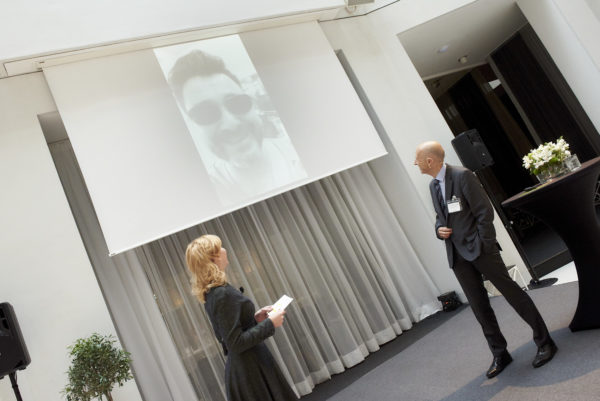 Barbara Bertolini hatte eine Überraschung für Univ.-Prof. Dr. Martin Kocher: Hier mit der Videoeinspielung von RockStar-Coffee Gründer Stefan Huber